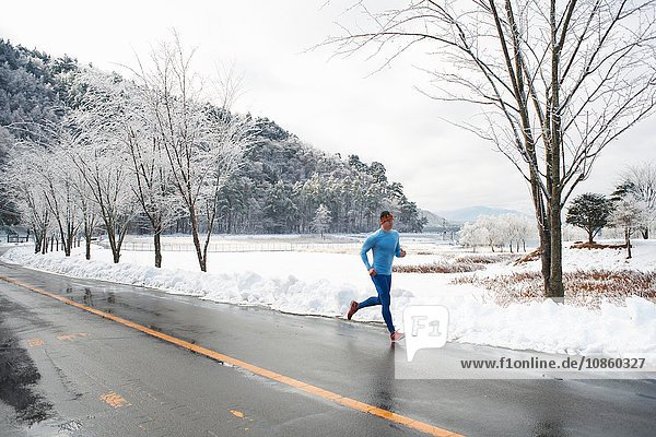 Älterer männlicher Läufer läuft im Winter auf der Straße  Kawaguchiko-See  Berg Fuji  Japan