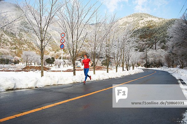 Männlicher Läufer  der im Winter auf der Straße läuft  Kawaguchiko-See  Berg Fuji  Japan