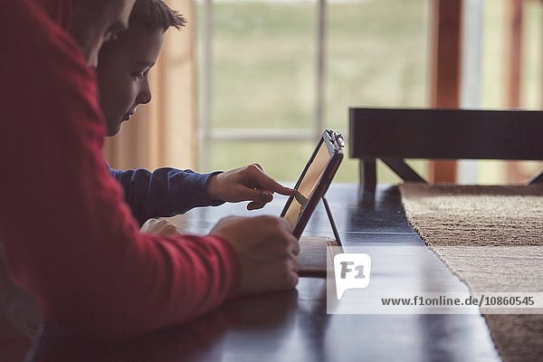 Vater und Sohn benutzen drahtloses digitales Tablet zu Hause