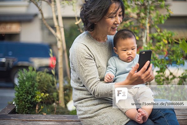 Großmutter zeigt ihrem Enkel im Freien ein Smartphone