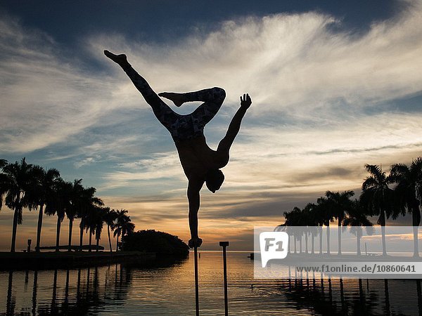 Mature man balancing on pole in water dusk South Pointe Park South Beach Miami Florida USA