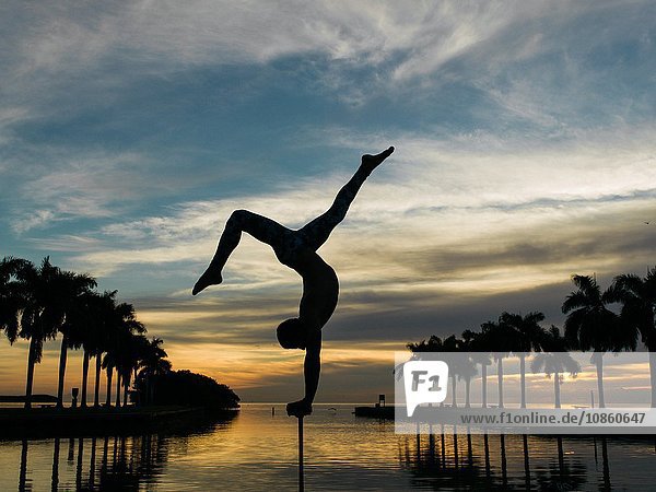 Mature man balancing on pole dusk South Pointe Park South Beach Miami Florida USA