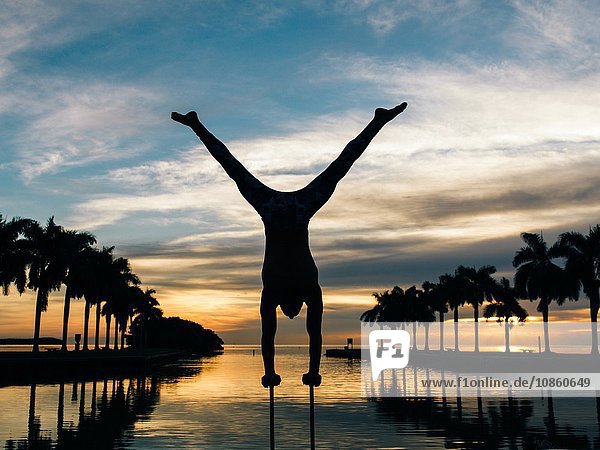 Mature man balancing on poles dusk South Pointe Park South Beach Miami Florida USA