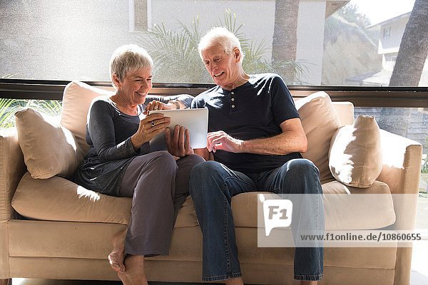 Senior couple  relaxing on sofa  looking at digital tablet