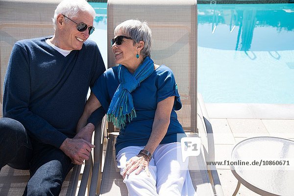 Älteres Ehepaar entspannt sich auf Liegestühlen am Pool