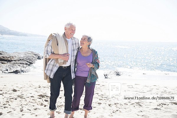 Älteres Ehepaar geht am Strand spazieren  lächelnd