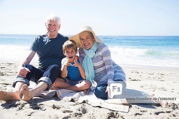 Porträt der Großeltern und des Enkels,  am Strand sitzend,  lächelnd