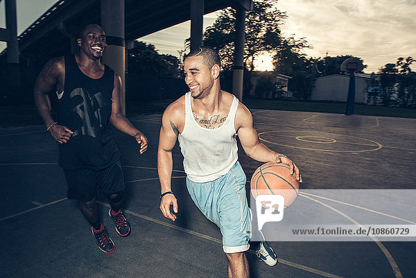 Young men playing basket ball on basketball court smiling