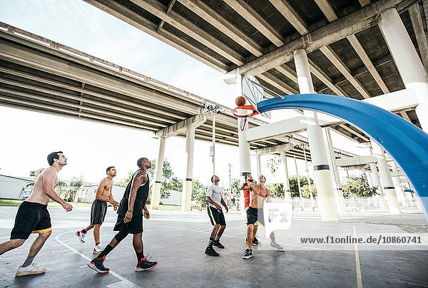 Men on basketball court watching basketball go through hoop