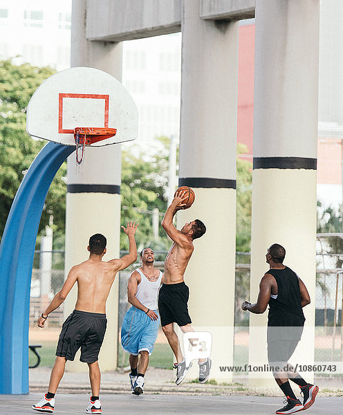 Side view of man in mid air holding basketball jumping for hoop