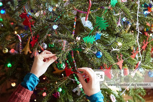 Frauenhände bereiten Weihnachtsschmuck am Weihnachtsbaum vor