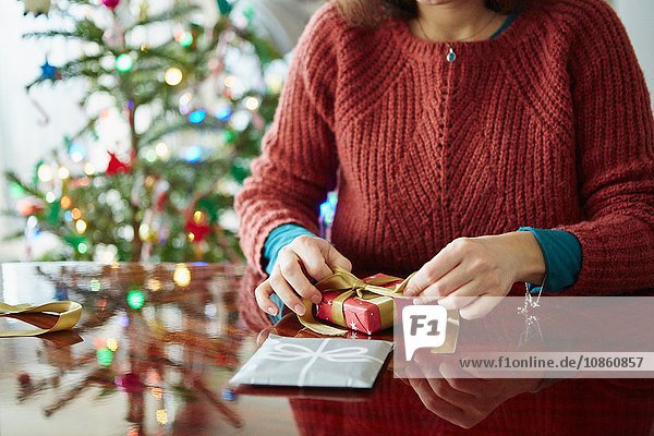 Ausschnitt einer Frau  die am Tisch ein Weihnachtsgeschenk verpackt