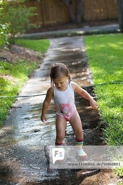 Child in wellies playing in puddle of water
