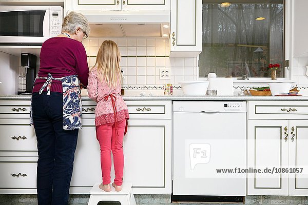 Rückansicht von Mädchen und Großmutter am Küchenherd stehend