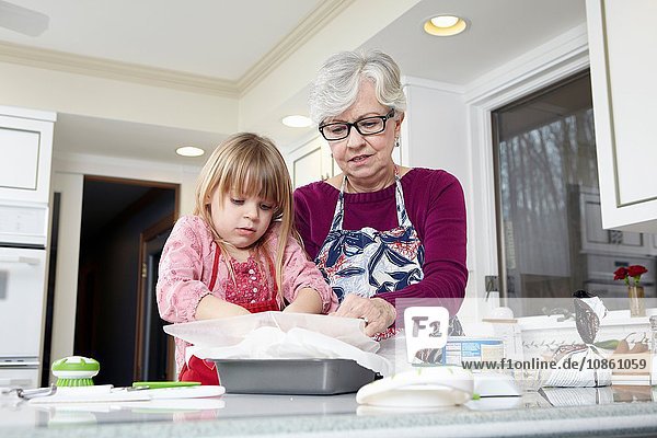 Mädchen und Großmutter bereiten an der Küchentheke fettdichtes Papier vor