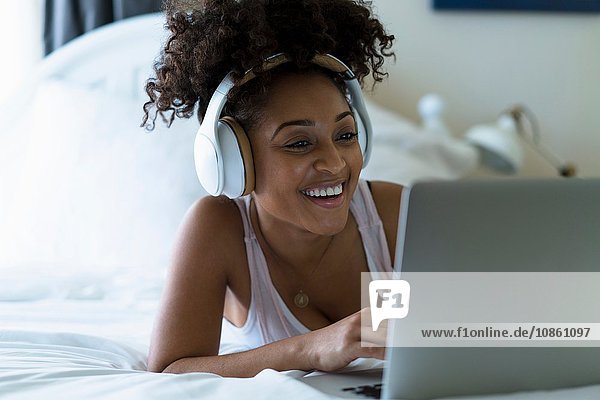 Frau im Schlafzimmer  benutzt Laptop  trägt Kopfhörer
