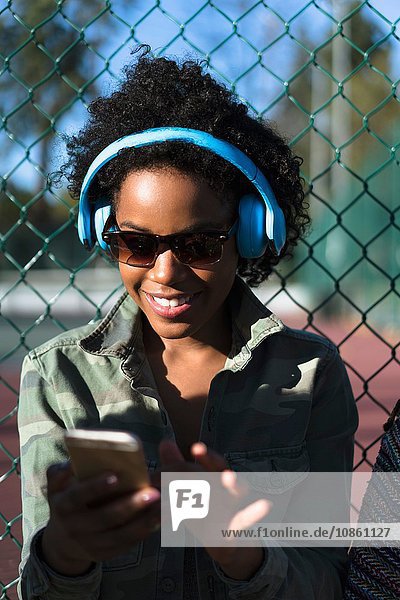 Frau im Freien  mit Kopfhörern  mit Smartphone