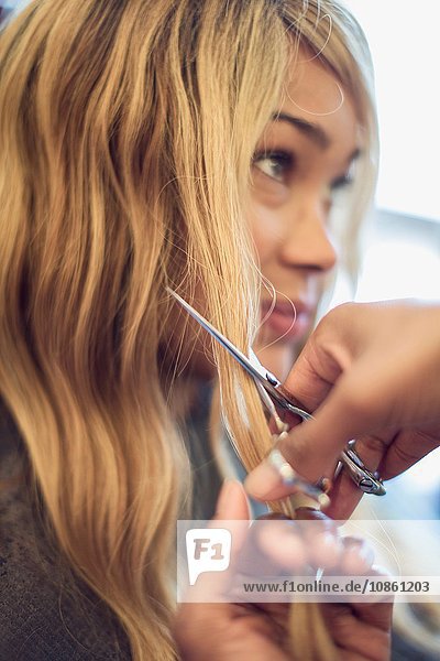 Stylist cutting woman's hair in hair salon