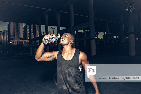 Man wearing vest drinking water from plastic bottle smiling