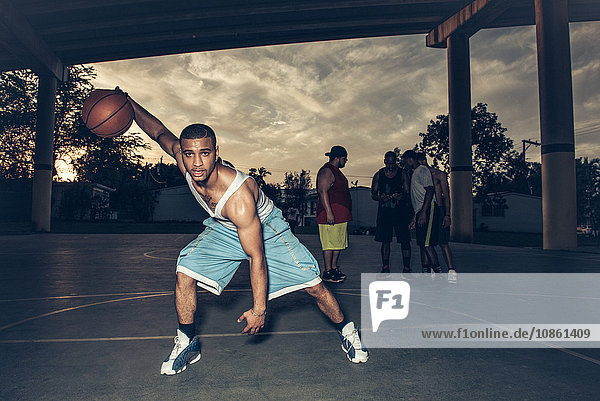 Man on basketball court bending forward holding basketball