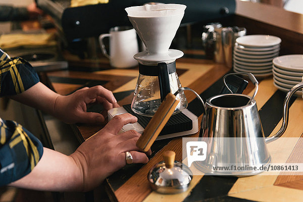 Nahaufnahme der Hände der Kellner die an der Kaffeetheke Kaffeefilter zubereiten