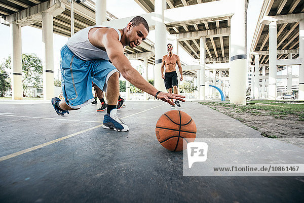 Men on basketball court reaching for basketball