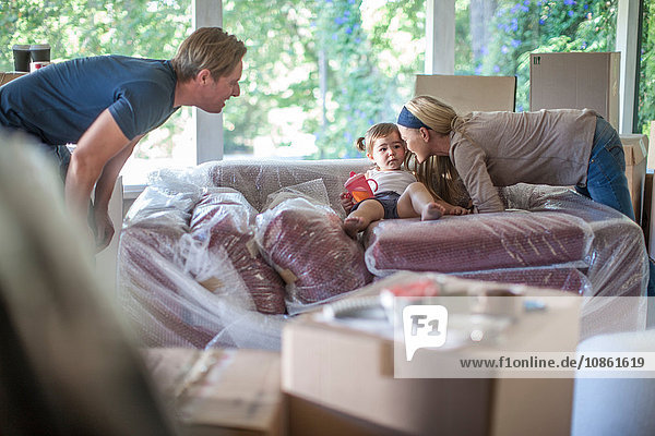 Umzug: Junges Mädchen sitzt auf einem Sofa mit Luftpolsterfolie
