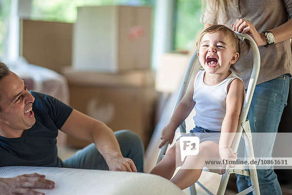 Umzug: Vater und Tochter lachen  Tochter sitzt auf einem Tritthocker