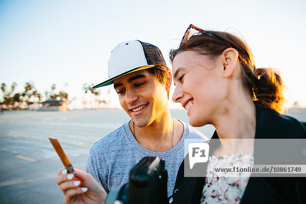 Young couple looking at instant photograph at coast  Venice Beach  California  USA