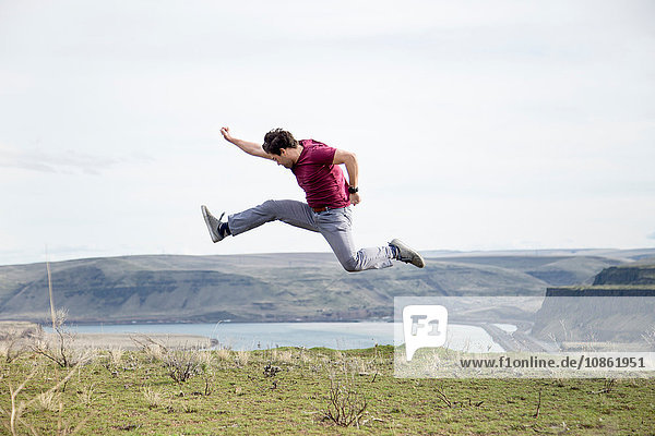Man jumping  in mid air  on mountain top  Colombia River Gorge  Washington  USA