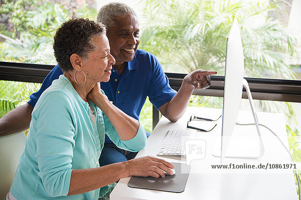 Älteres Ehepaar am Tisch sitzend  mit Computer