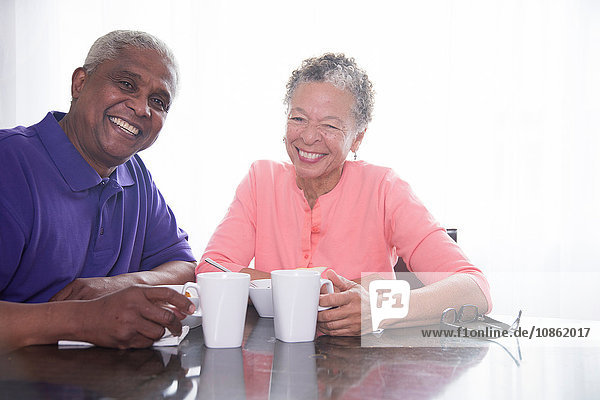 Porträt eines älteren Ehepaares beim Frühstück  lächelnd