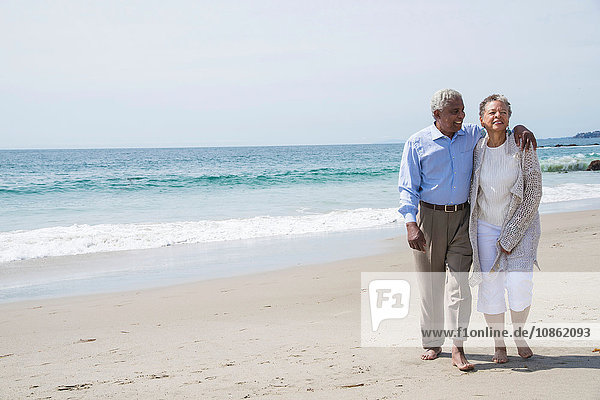 Senior couple waking together on beach  smiling