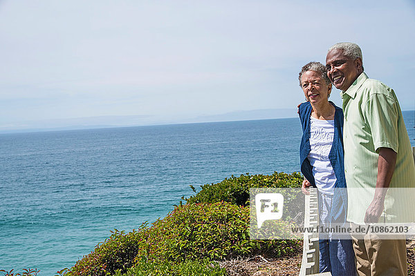 Senior couple standing outside  near ocean  looking at view