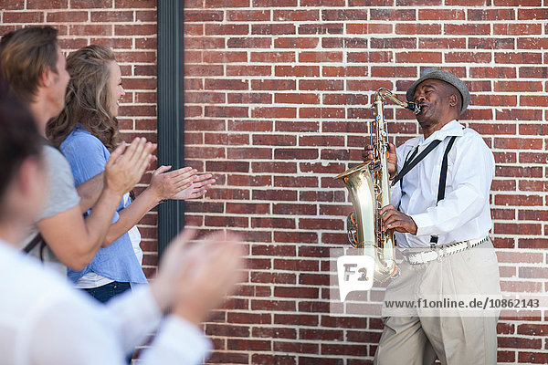 Straßenmusikant  spielt Saxophon  unterhält Fußgänger  Fußgänger klatschen
