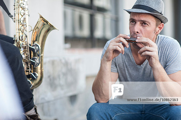 Straßenmusikant  der Mundharmonika spielt