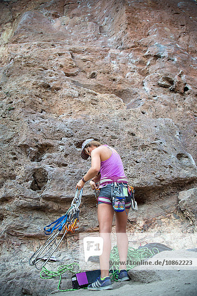Rückansicht einer Frau an einer Felswand mit Kletterausrüstung