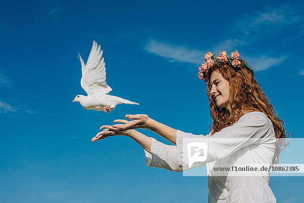 Teenager-Mädchen lässt weiße Taube in den Himmel frei