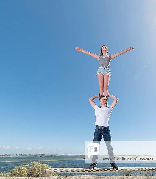 Paar übt Partner-Yoga auf der Strandbank