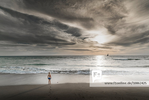 Junge mit Blick auf das Meer und den dramatischen Himmel von Venice Beach  Kalifornien  USA