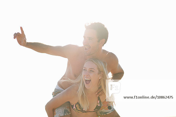 Woman giving man piggyback looking away smiling