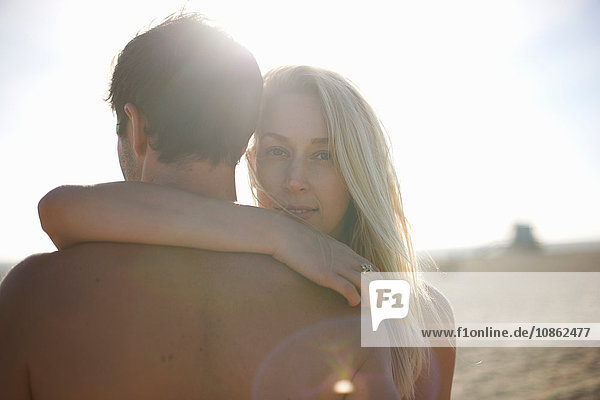 Over shoulder view of woman looking at camera arm around man