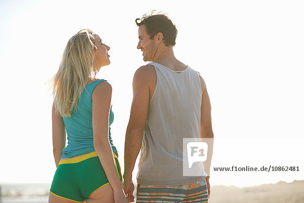 Rückansicht des Paares am Strand von Angesicht zu Angesicht lächelnd