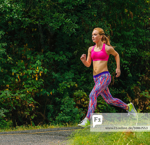 Teenage female runner running along rural road