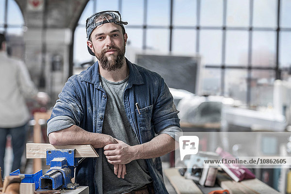 Portrait of young male carpenter in antique restoration workshop