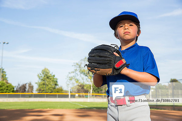 Porträt eines selbstbewussten Jungen  der beim Baseballtraining einen Baseballhandschuh trägt