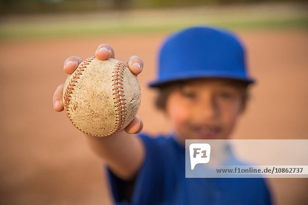 Unscharfes Porträt eines Jungen  der beim Baseball-Training den Ball hochhält