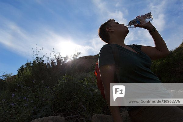 Silhouette einer Frau  die Wasser aus einer Plastikflasche trinkt