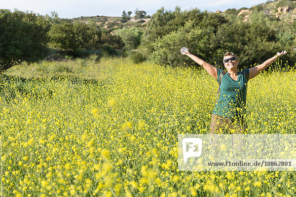Wanderfrau auf Wildblumenwiese  Arme erhoben