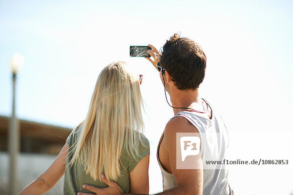 Rear view of couple taking smartphone selfie at Venice Beach Los Angeles California USA